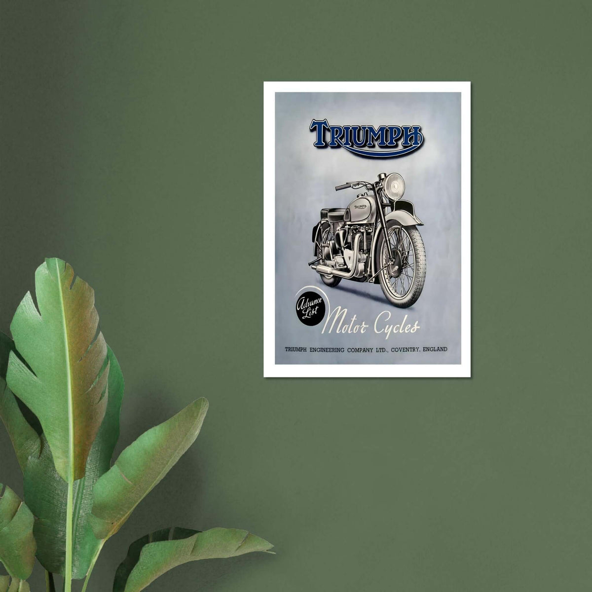 vintage Triumph motorcycle poster framed on a wall with green background and palm leaves.