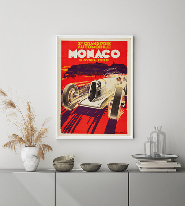 White race car against a red background with the text Monaco in white letters